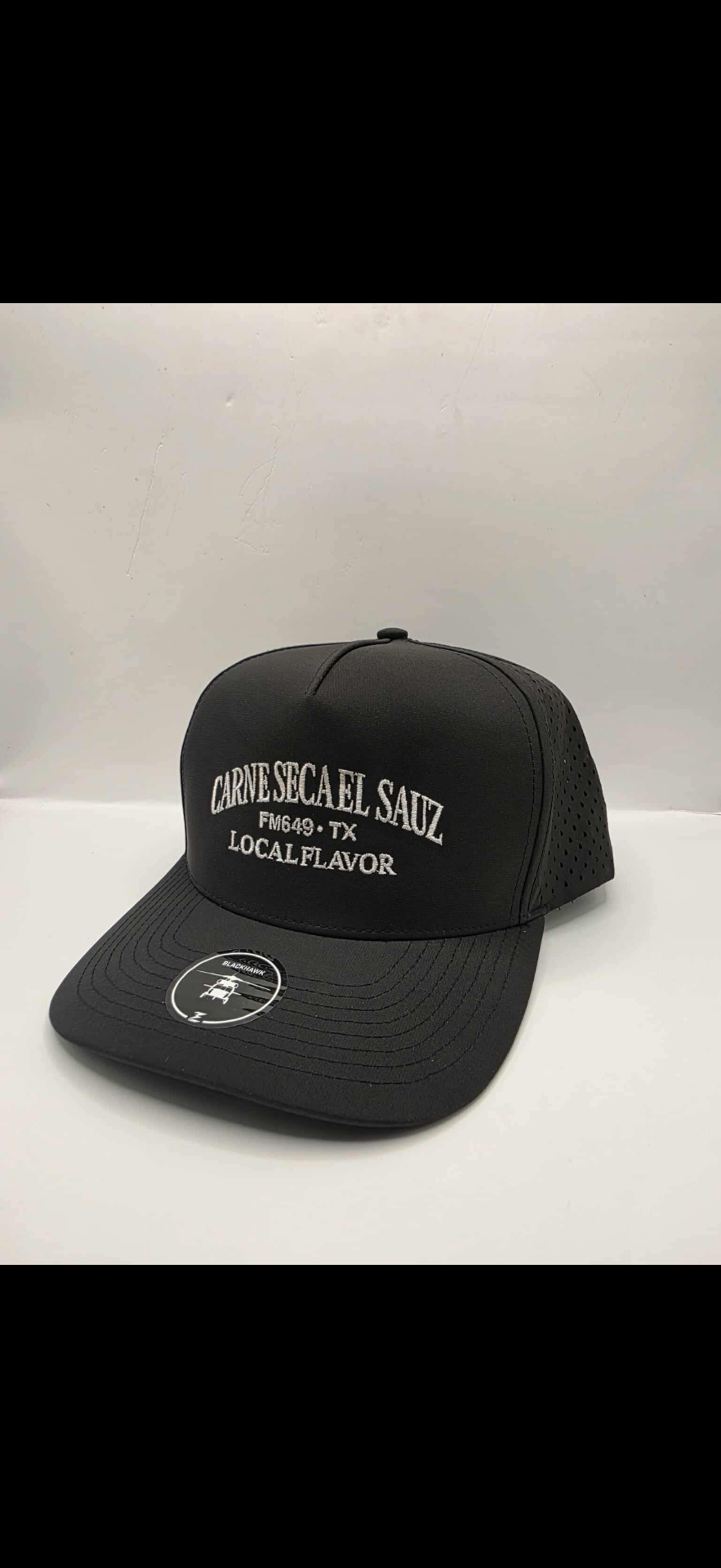 Black performance cap with white 'Carne Seca El Sauz FM649 TX Local Flavor' embroidery